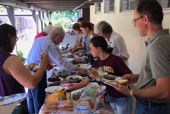 Everyone pitches in to make the burgers and bbq for the back-to-school Pentecost BBQ